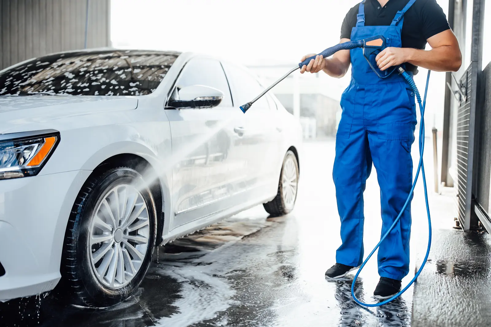 Professional washing a car with a pressure washer