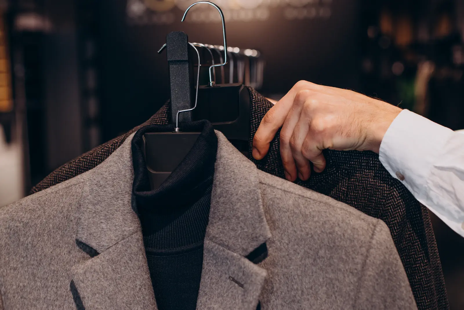 Young man choosing cloths in menswear shop
